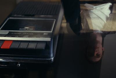 Split Diopter of a Tape recorder on a glass table with a man in the reflection.