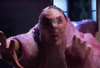 A woman covered in pink blob stuff lunges forward.