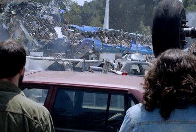 Two men stand before a demolished airliner.